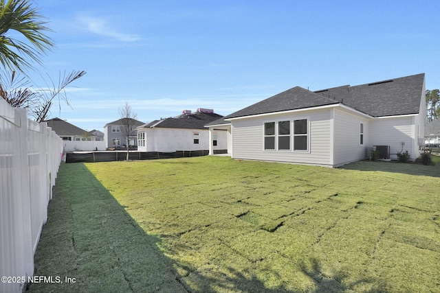 rear view of property with cooling unit and a yard