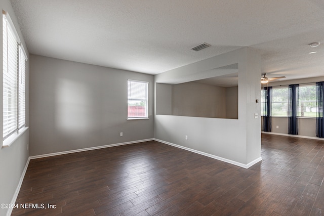 unfurnished room with a textured ceiling, ceiling fan, and dark wood-type flooring