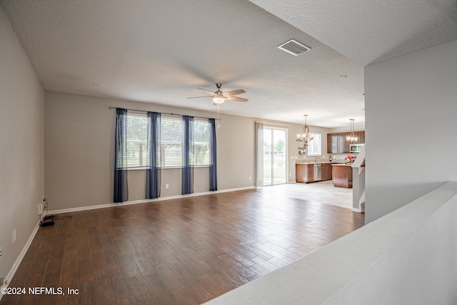 unfurnished room with ceiling fan with notable chandelier, wood-type flooring, and a textured ceiling