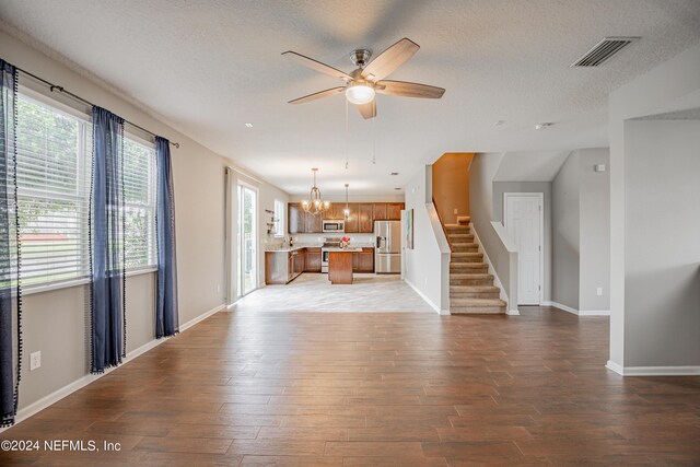 unfurnished living room featuring a textured ceiling, sink, wood-type flooring, and ceiling fan with notable chandelier