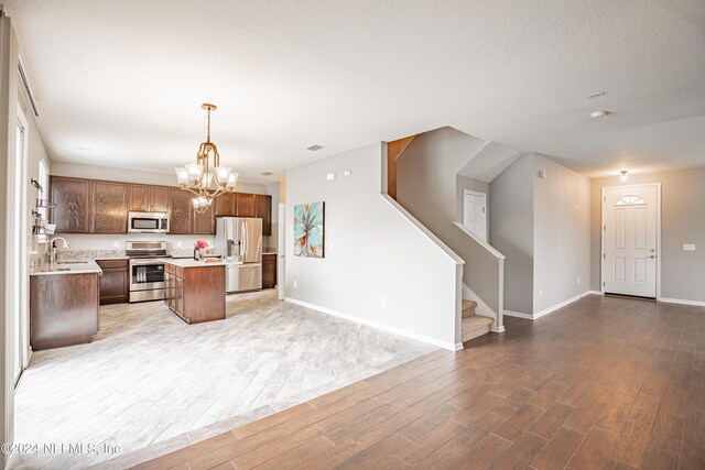 kitchen with sink, hanging light fixtures, stainless steel appliances, a notable chandelier, and a kitchen island