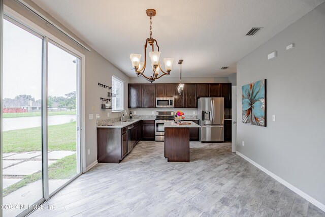 kitchen featuring sink, decorative light fixtures, a kitchen island, dark brown cabinets, and stainless steel appliances