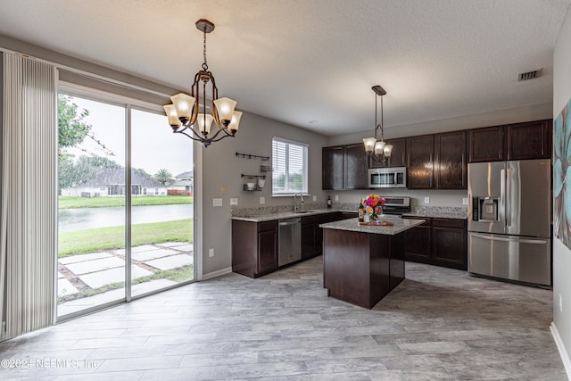 kitchen with pendant lighting, a center island, stainless steel appliances, and sink