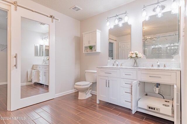 bathroom with vanity, a shower with shower door, a textured ceiling, and toilet