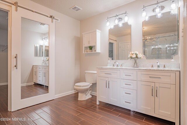 bathroom featuring a textured ceiling, vanity, toilet, and walk in shower