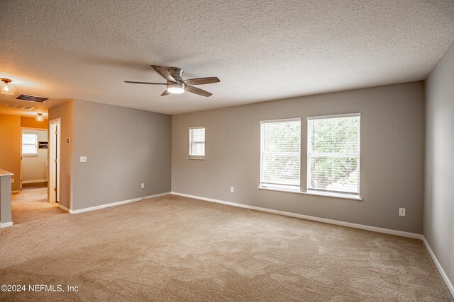 empty room with light carpet, ceiling fan, and a textured ceiling