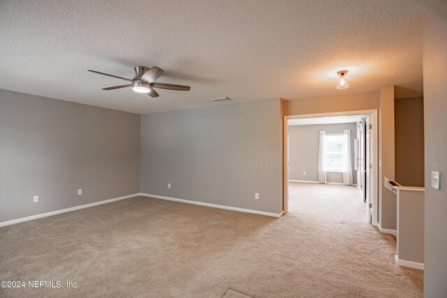 empty room with light carpet, ceiling fan, and a textured ceiling