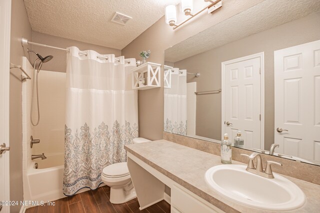 full bathroom with shower / bath combo, toilet, a textured ceiling, and vanity