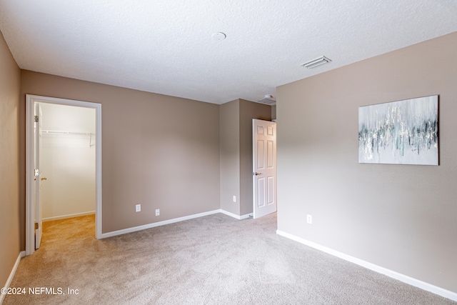 spare room with a textured ceiling and light carpet