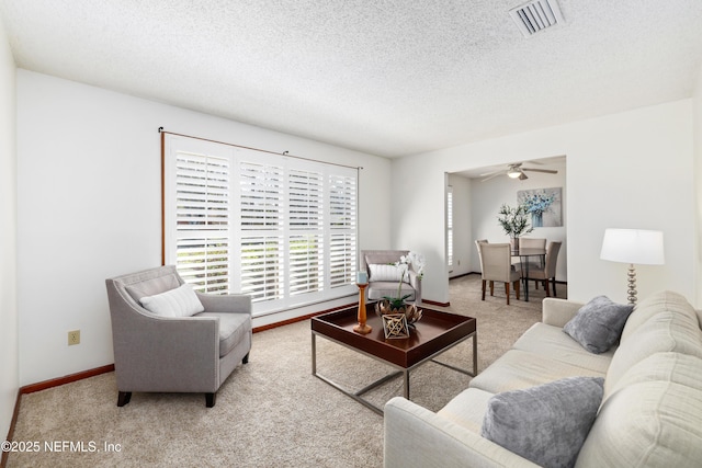 carpeted living room featuring ceiling fan and a textured ceiling