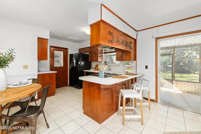 kitchen featuring kitchen peninsula, black refrigerator with ice dispenser, sink, and stainless steel gas stovetop