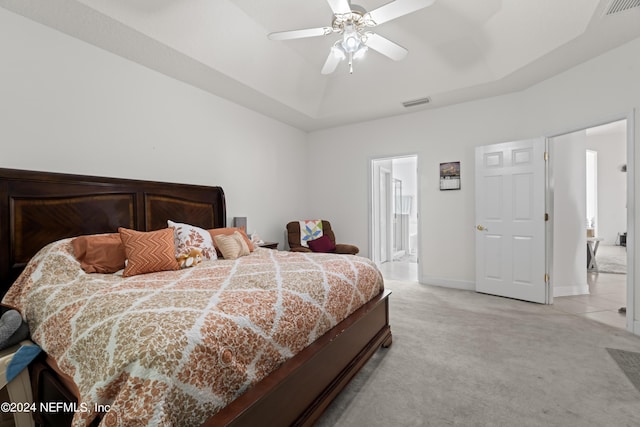 bedroom featuring visible vents, a tray ceiling, baseboards, and light colored carpet