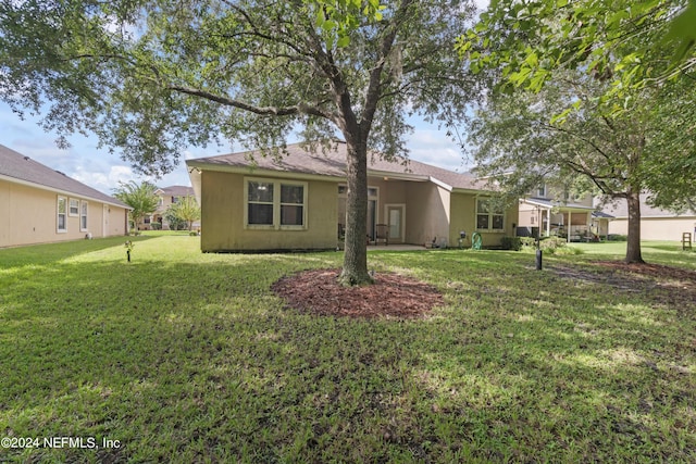 back of property featuring a lawn and stucco siding