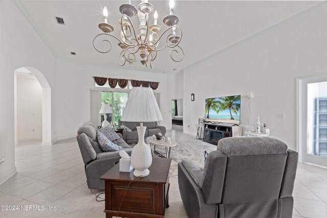 living area featuring arched walkways, light tile patterned floors, visible vents, a towering ceiling, and a chandelier