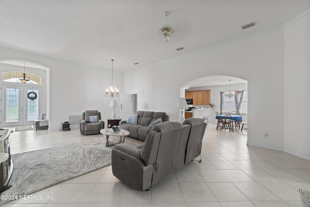 living area with light tile patterned floors, visible vents, arched walkways, an inviting chandelier, and french doors