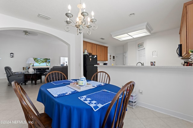 dining area with arched walkways, light tile patterned flooring, visible vents, baseboards, and an inviting chandelier