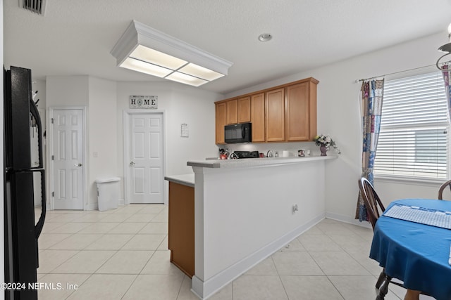 kitchen with visible vents, brown cabinetry, a peninsula, light countertops, and black appliances