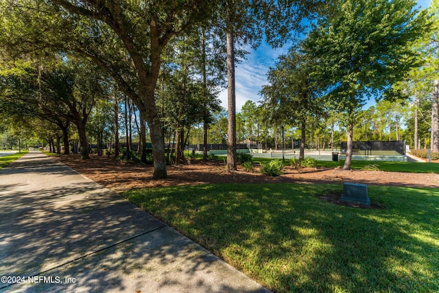 view of community featuring a tennis court and fence