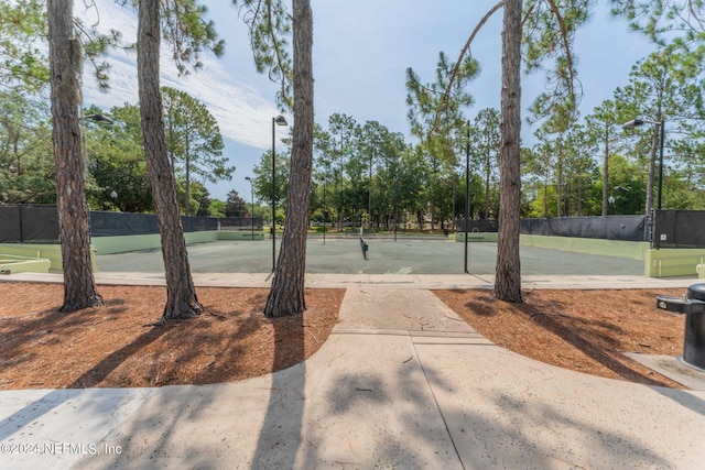 view of home's community featuring a tennis court and fence