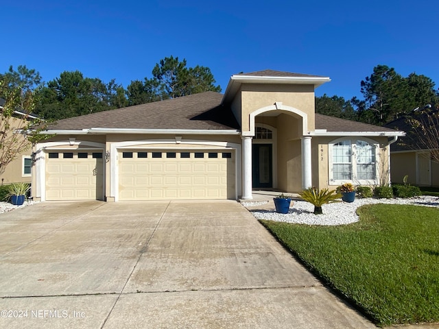 view of front of property with concrete driveway, roof with shingles, an attached garage, a front lawn, and stucco siding