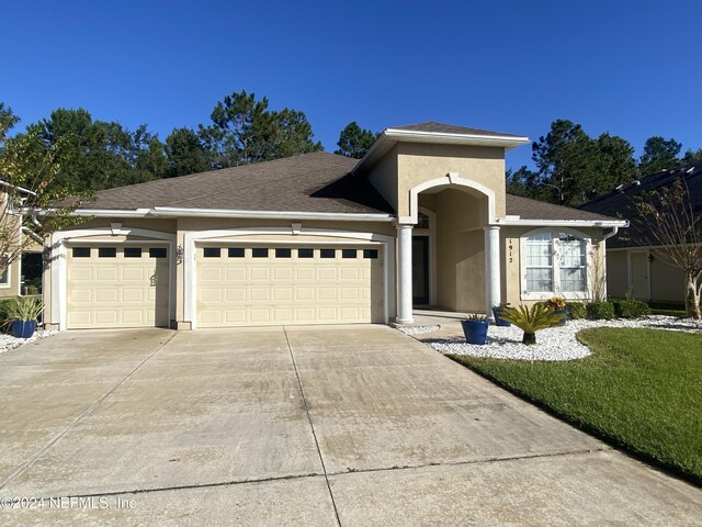 1912 White Dogwood Ln, Fleming Island, FL 32003 - view of front facade with concrete driveway, an attached garage, a shingled roof, and stucco siding