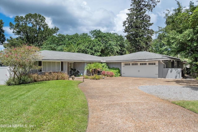 ranch-style home featuring driveway, an attached garage, a shingled roof, and a front yard