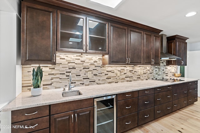 kitchen with light wood-type flooring, tasteful backsplash, wine cooler, sink, and wall chimney range hood