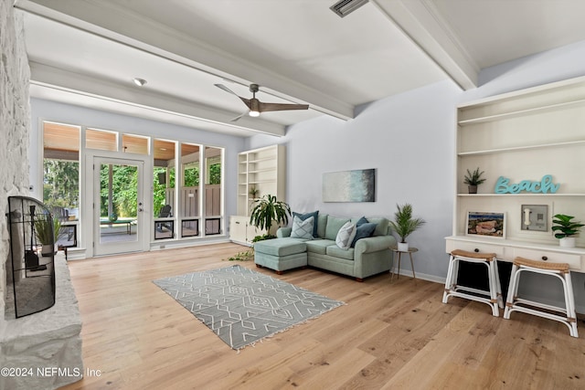 living area with built in shelves, wood finished floors, visible vents, a ceiling fan, and beamed ceiling