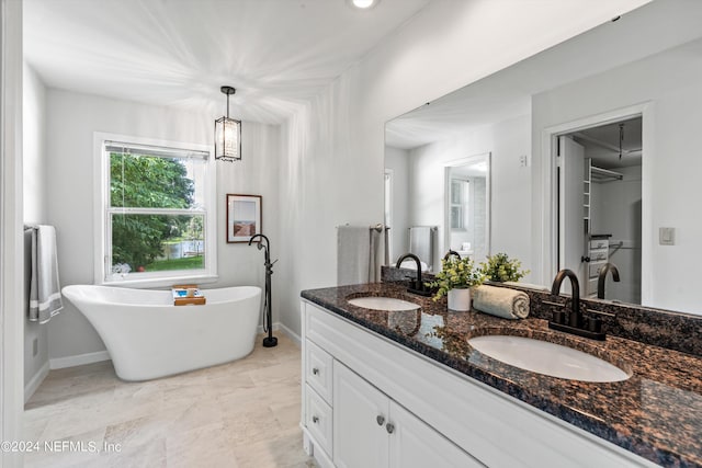 bathroom featuring double vanity, a freestanding bath, baseboards, and a sink