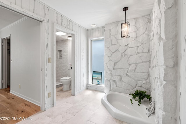 full bathroom featuring ornamental molding, baseboards, toilet, and a bath