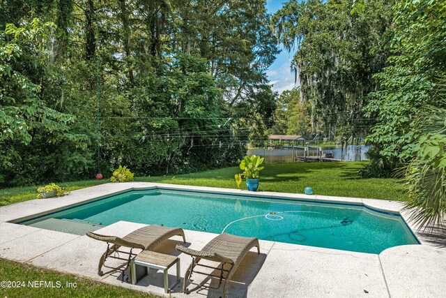 view of pool featuring a water view, a lawn, and a patio area