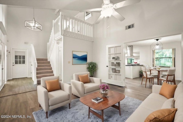 living room with ceiling fan with notable chandelier, high vaulted ceiling, and hardwood / wood-style floors