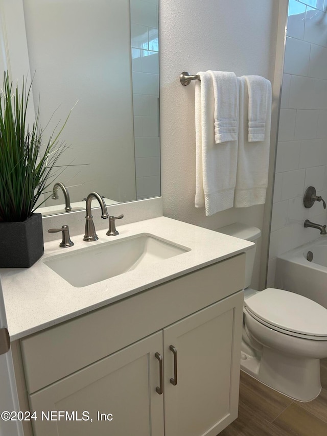 full bathroom featuring vanity, hardwood / wood-style flooring, toilet, and tiled shower / bath combo