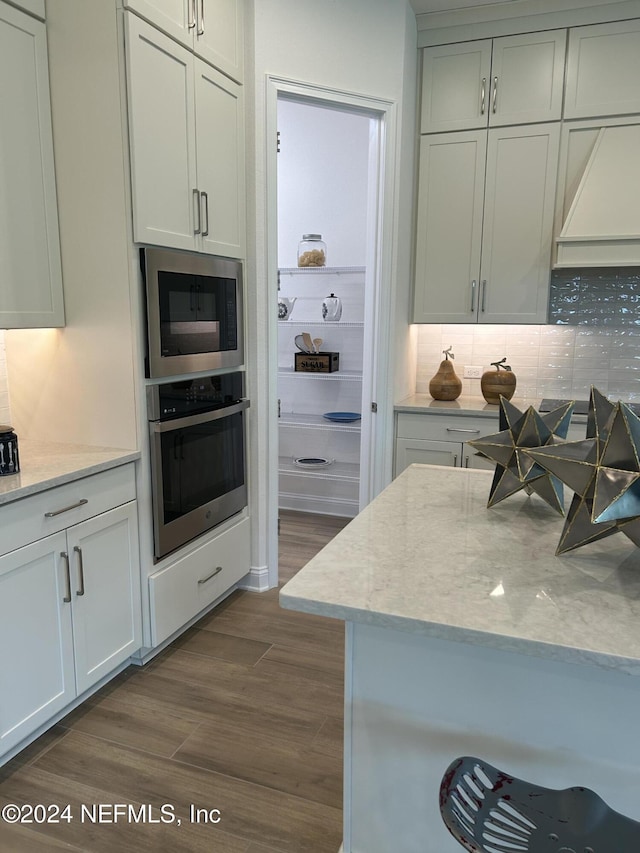 95246 Golden Glow Dr, Fernandina Beach, FL 32034 - kitchen featuring oven, built in microwave, dark wood finished floors, backsplash, and light stone countertops