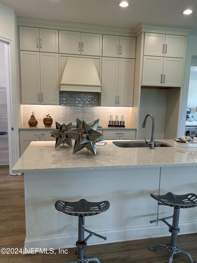 95246 Golden Glow Dr, Fernandina Beach, FL 32034 - kitchen with custom range hood, a kitchen breakfast bar, light stone countertops, dark wood finished floors, and backsplash