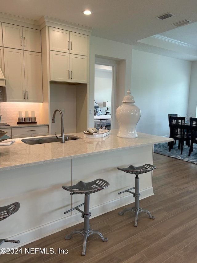 kitchen featuring a kitchen breakfast bar, light stone counters, sink, and dark hardwood / wood-style floors