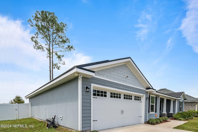 view of side of home featuring a garage, concrete driveway, and fence