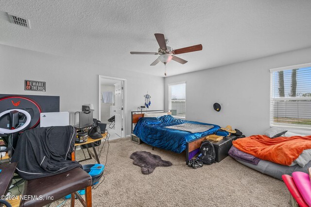 carpeted bedroom with a textured ceiling, ceiling fan, and multiple windows