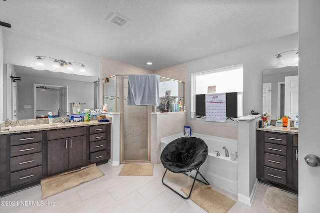 bathroom featuring tile patterned flooring, vanity, independent shower and bath, and a textured ceiling