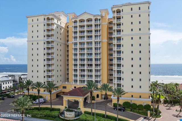 view of building exterior featuring a water view and a beach view