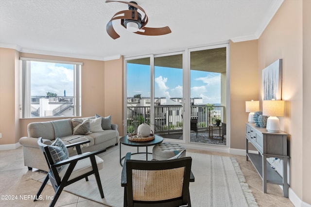 living area featuring baseboards, light tile patterned floors, a ceiling fan, and crown molding