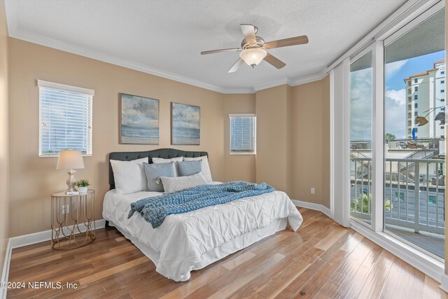 bedroom featuring ceiling fan, ornamental molding, wood-type flooring, and multiple windows