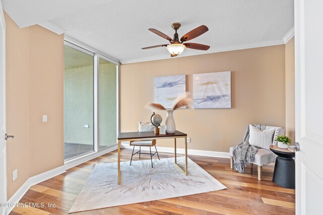 office with hardwood / wood-style flooring, a textured ceiling, expansive windows, ceiling fan, and ornamental molding