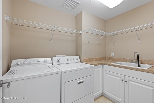 laundry room featuring cabinets, washing machine and clothes dryer, and sink