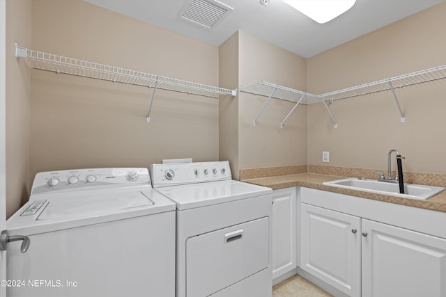 washroom with washer and clothes dryer, cabinet space, a sink, and visible vents