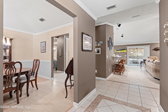 hallway featuring ornamental molding, vaulted ceiling, and light tile patterned floors