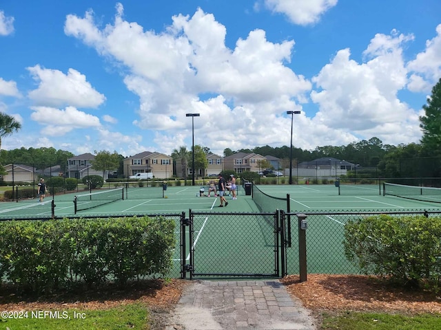 view of sport court featuring a gate, fence, and a residential view