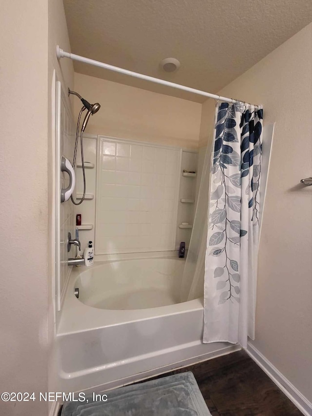 bathroom with hardwood / wood-style floors, shower / tub combo with curtain, and a textured ceiling