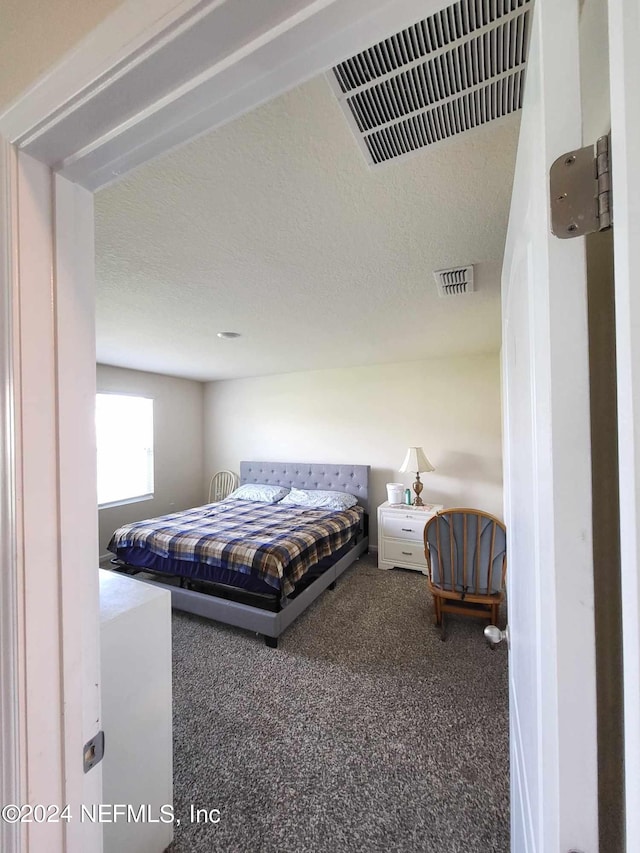 carpeted bedroom featuring visible vents and a textured ceiling