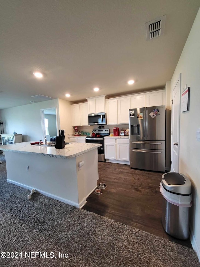 kitchen featuring white cabinetry, dark hardwood / wood-style flooring, light stone counters, an island with sink, and appliances with stainless steel finishes